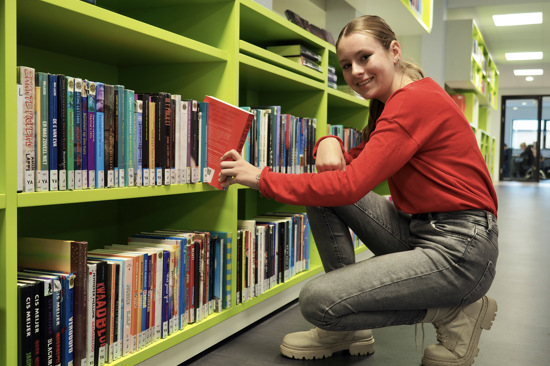 Leerling grijpt boek uit boekenkast